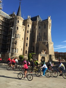 Gaudi's bishops palace being passed by a horde of cyclists